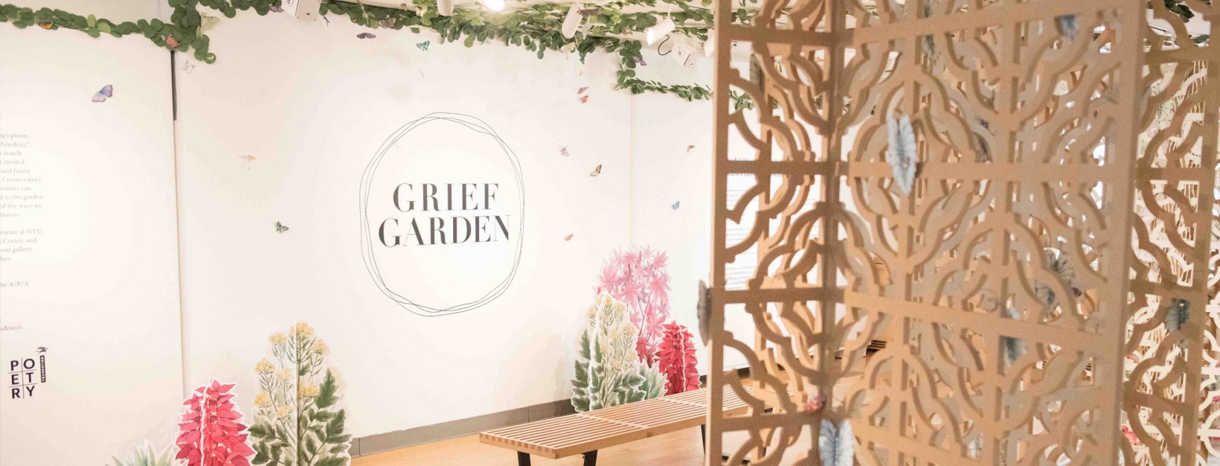A photograph of the installation Grief Garden features paper plants, trellises, and a logo that reads Grief Garden