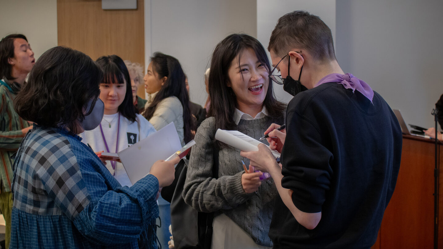 A photograph of a crowd mingling and getting books signed at an A/P/A Institute event at 20 Cooper Square.