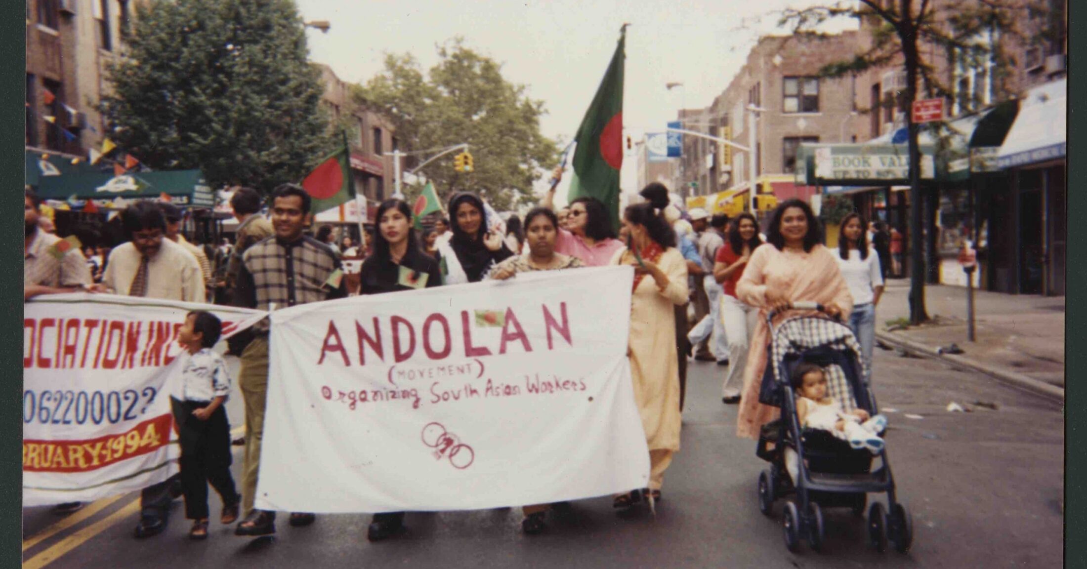 Andolan members walk in a group behind a sign that reads