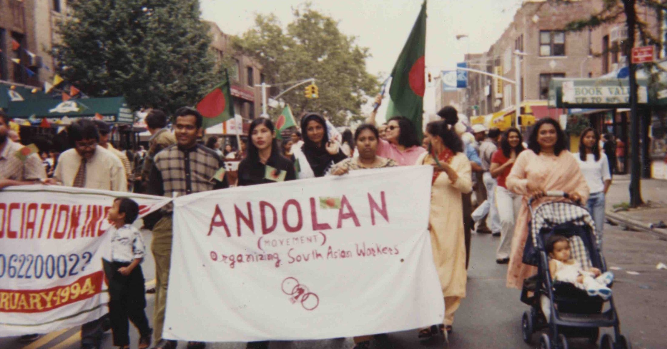 Andolan members walk in a group behind a sign that reads