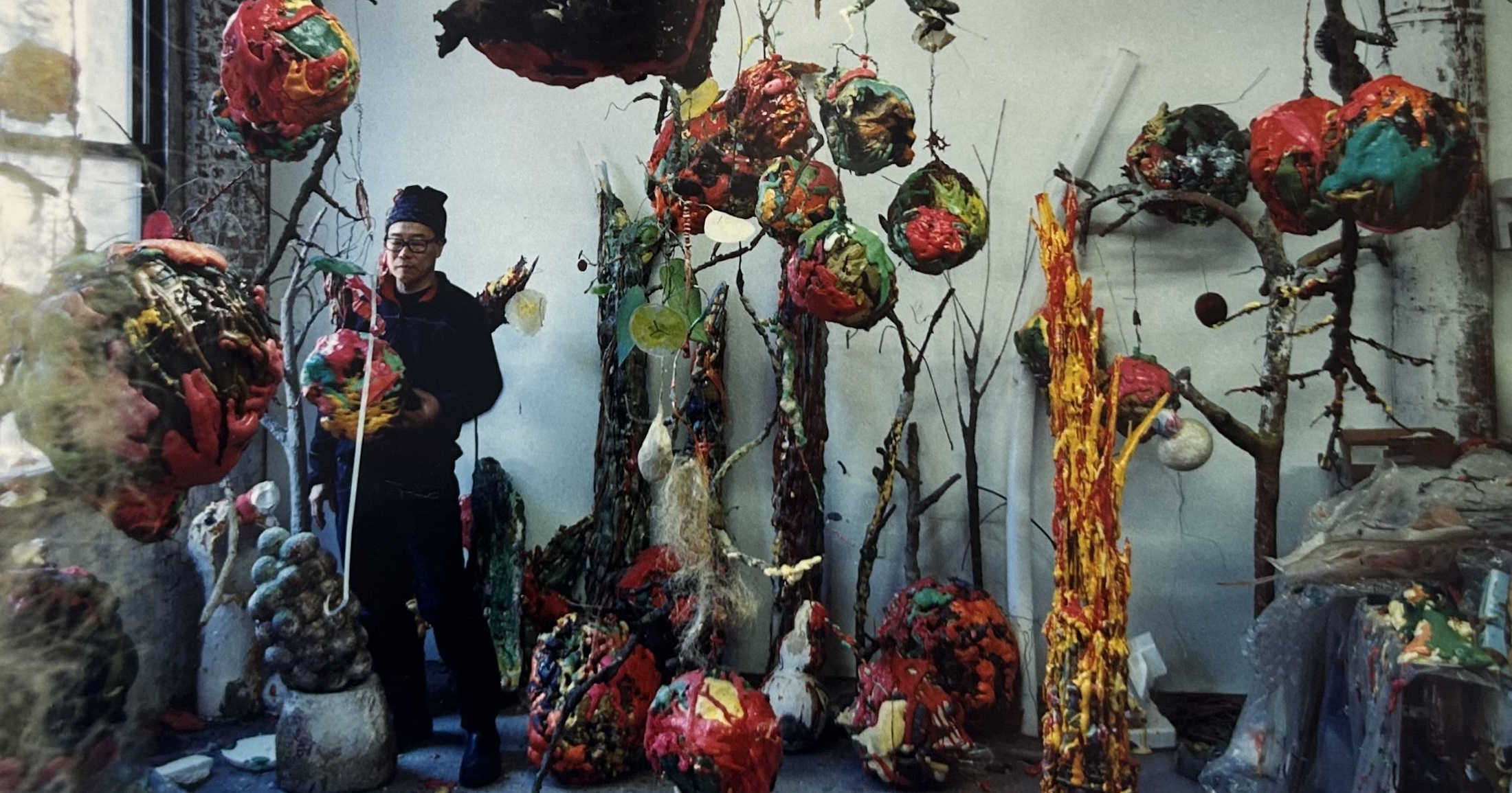 Ming Fay surrounded by vibrant sculptures resembling dripping spheres.
