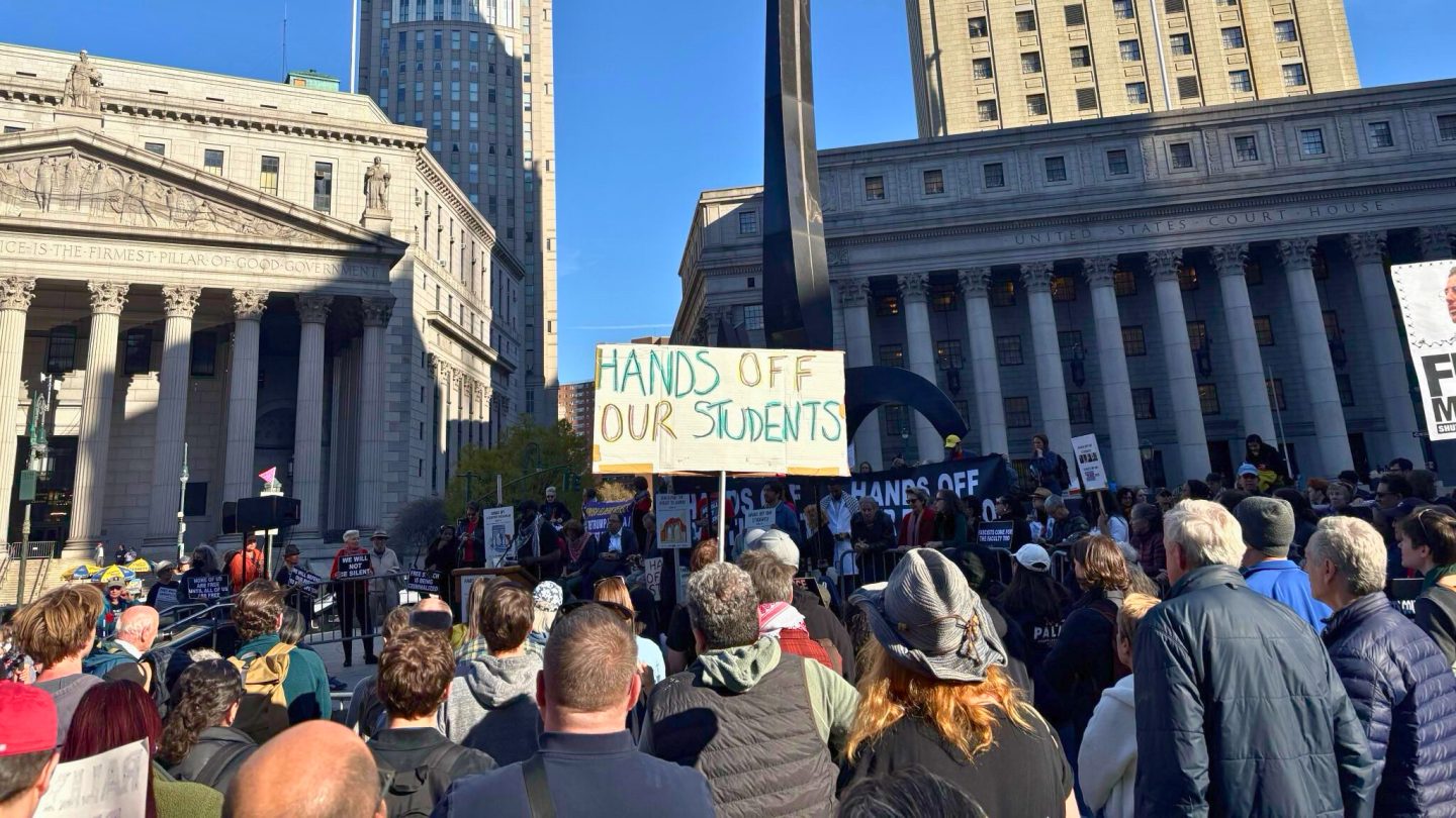 A photograph from the April 17, 2025 "Right to Learn Rally" at Foley Square. A crowd is featured in the foreground, and a sign that reads 'Hands off our students' is held by one of them.
