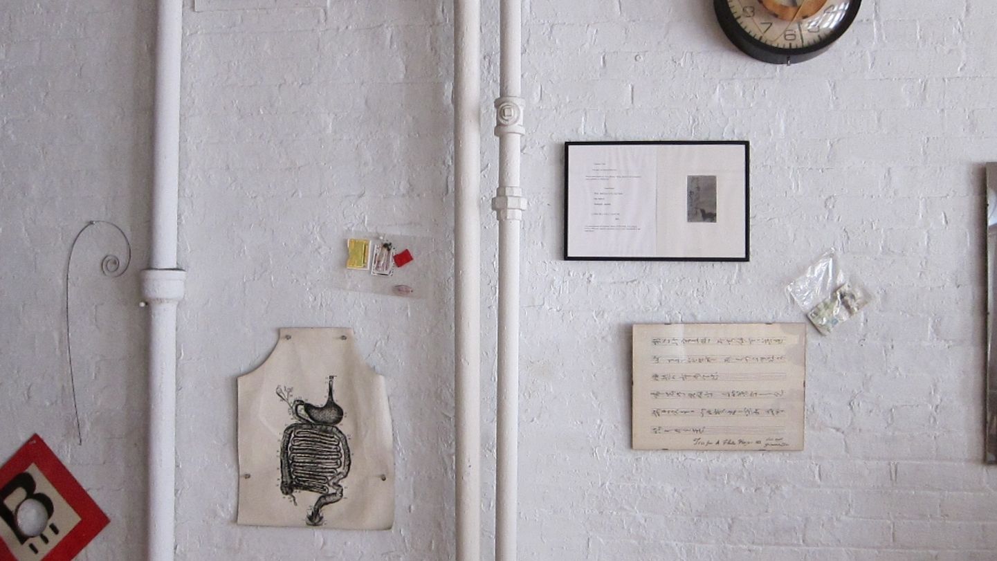 A photograph of art and objects hanging on a white wall.